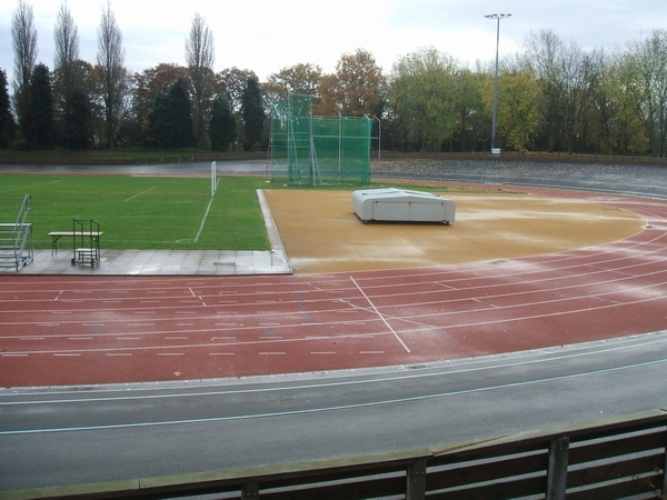 Pusty stadion z bieżnią i trybunami, bez zawodników.